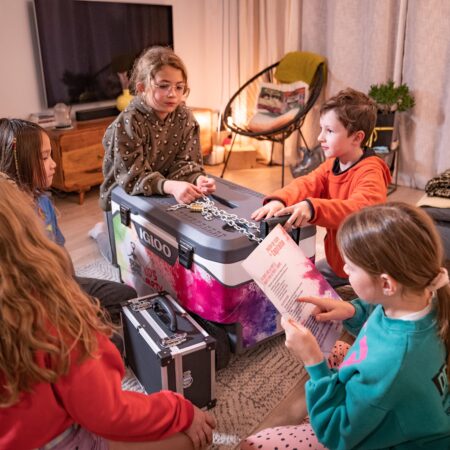 Groupe d'enfants autour de la glacière Kids Party, ils décryptent les énigmes pour déguster les produits normands